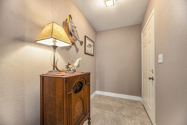 doorway with a textured wall, baseboards, and a textured ceiling