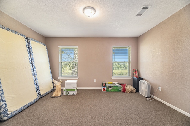 rec room with visible vents, baseboards, carpet floors, a textured wall, and a textured ceiling