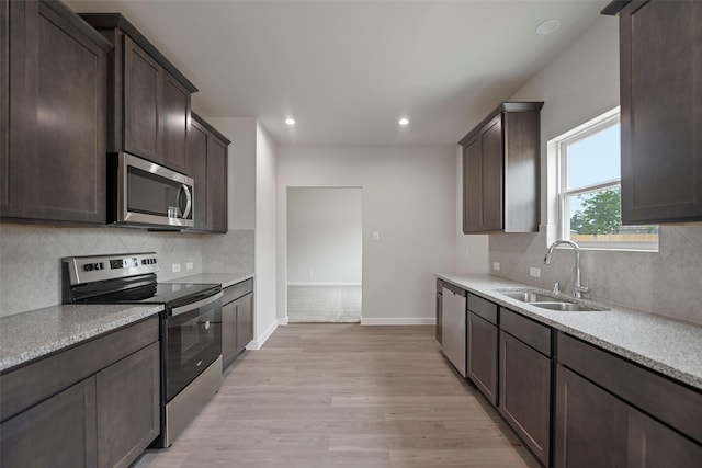 kitchen with tasteful backsplash, stainless steel appliances, light wood-type flooring, sink, and dark brown cabinetry