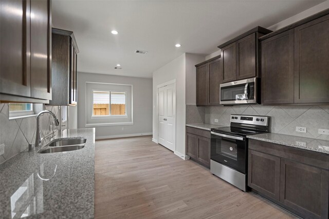 kitchen featuring light hardwood / wood-style flooring, stainless steel appliances, tasteful backsplash, sink, and light stone counters