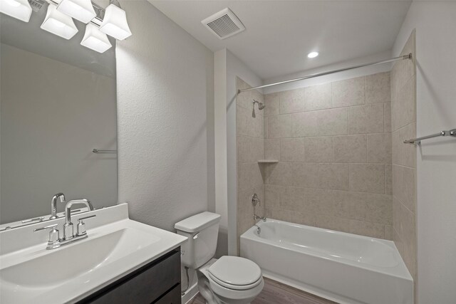 full bathroom featuring vanity, tiled shower / bath combo, wood-type flooring, and toilet