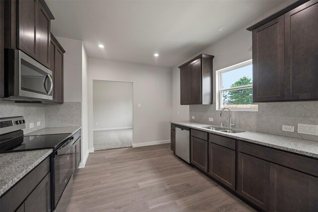 kitchen featuring tasteful backsplash, light hardwood / wood-style flooring, appliances with stainless steel finishes, and sink