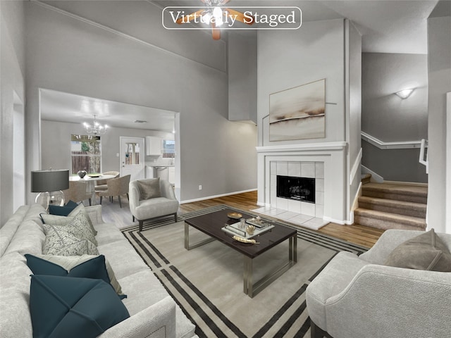 living room featuring high vaulted ceiling, hardwood / wood-style flooring, a tiled fireplace, and a chandelier