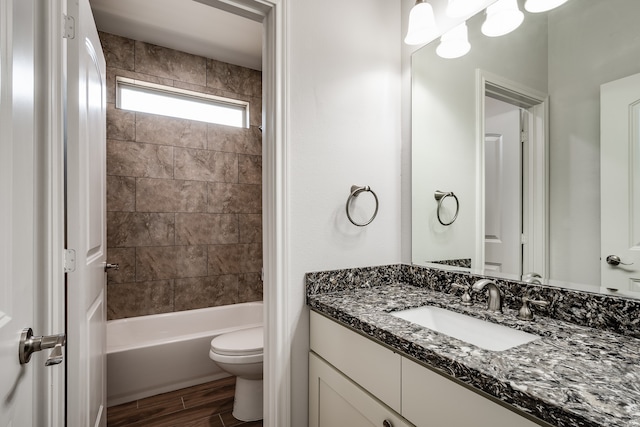 full bathroom with tiled shower / bath, vanity, and toilet