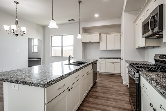 kitchen with sink, dark hardwood / wood-style flooring, hanging light fixtures, stainless steel appliances, and an island with sink