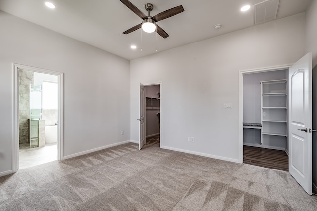 unfurnished bedroom with carpet floors, ceiling fan, a walk in closet, and ensuite bathroom