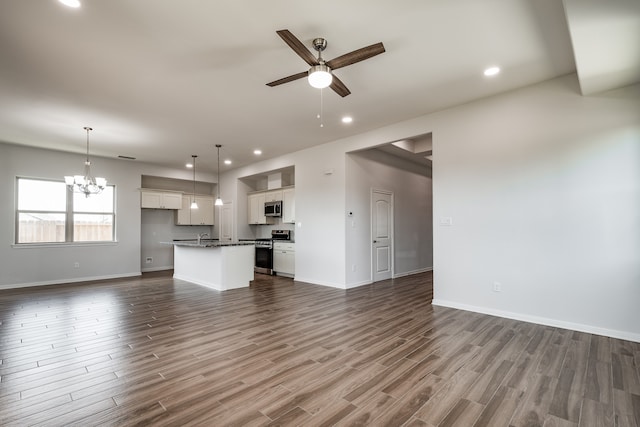 unfurnished living room featuring wood-type flooring, sink, and ceiling fan with notable chandelier