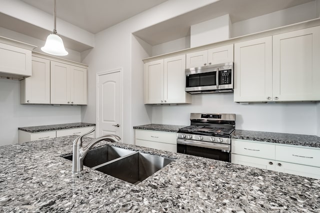 kitchen with appliances with stainless steel finishes, hanging light fixtures, sink, and white cabinetry