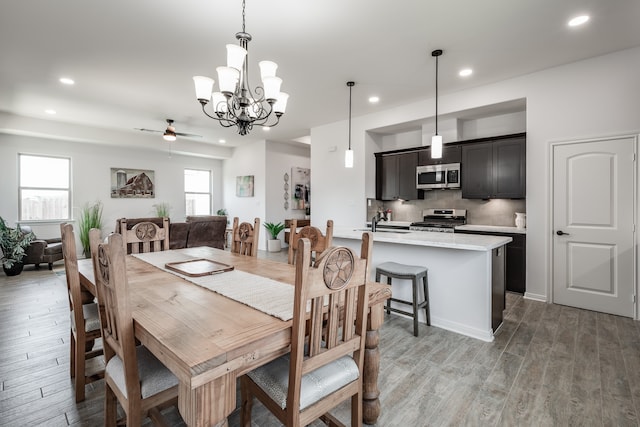 dining room featuring hardwood / wood-style flooring, ceiling fan with notable chandelier, and sink