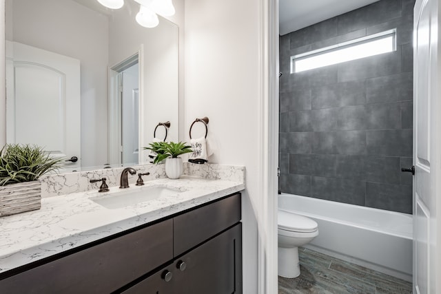 full bathroom with vanity with extensive cabinet space, tiled shower / bath combo, and toilet