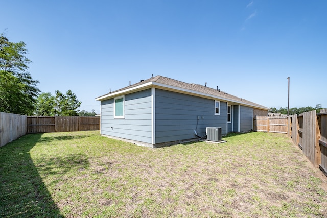 back of property featuring central air condition unit and a lawn