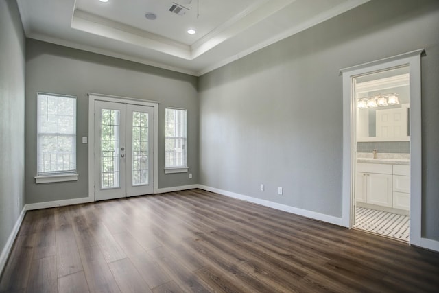 empty room featuring french doors, dark hardwood / wood-style flooring, a tray ceiling, and ornamental molding