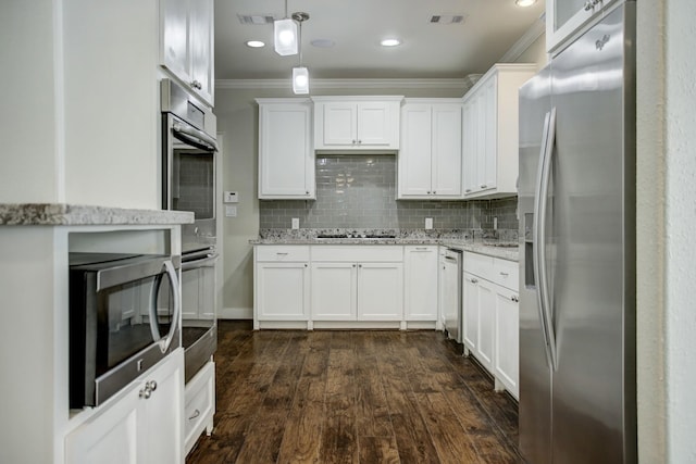 kitchen featuring appliances with stainless steel finishes, backsplash, dark wood-type flooring, white cabinetry, and ornamental molding