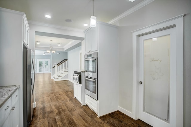 kitchen with appliances with stainless steel finishes, white cabinets, hanging light fixtures, and dark hardwood / wood-style floors