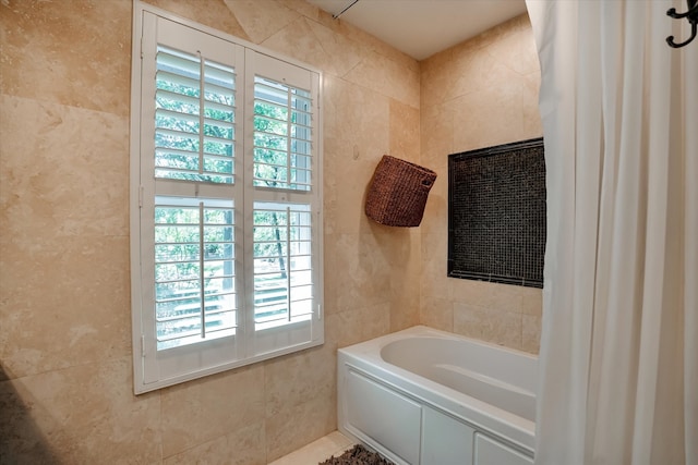 bathroom with shower / bathtub combination with curtain and tile walls