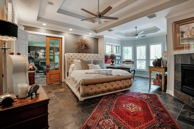 bedroom with a raised ceiling, a tile fireplace, crown molding, and ceiling fan