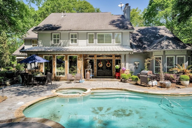 rear view of house featuring a swimming pool with hot tub, french doors, and a patio area