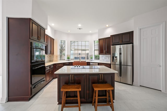 kitchen with tasteful backsplash, a center island, a breakfast bar area, and black appliances