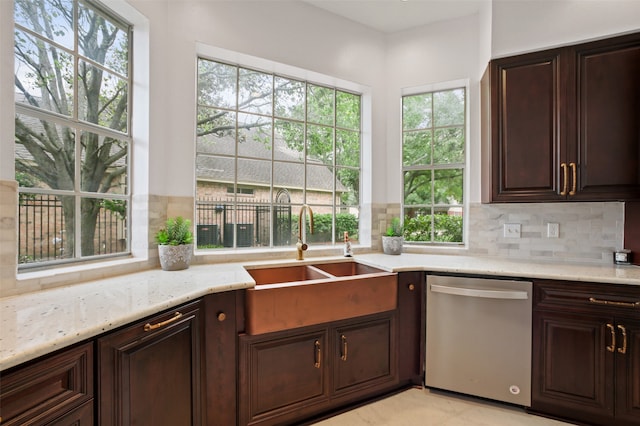 kitchen featuring dishwasher, backsplash, sink, light stone countertops, and dark brown cabinetry