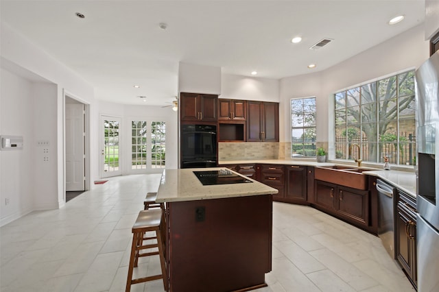 kitchen with a center island, decorative backsplash, a healthy amount of sunlight, and black appliances