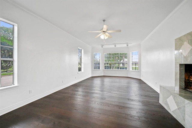 unfurnished living room with crown molding, a healthy amount of sunlight, dark hardwood / wood-style flooring, and a fireplace