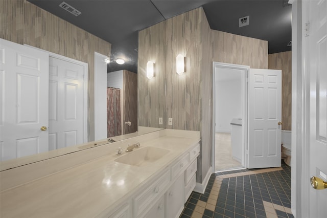 bathroom with vanity, wood walls, and toilet