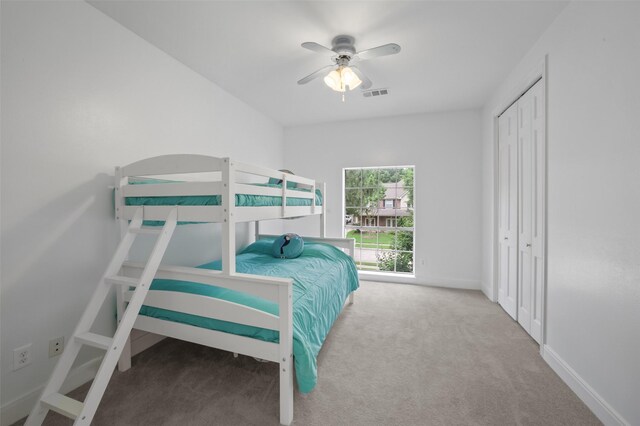 carpeted bedroom featuring ceiling fan and a closet