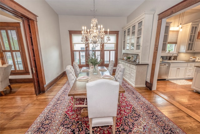 dining room featuring a notable chandelier, light hardwood / wood-style floors, a healthy amount of sunlight, and sink