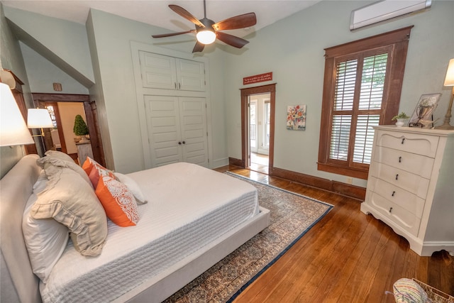 bedroom with a wall mounted air conditioner, a ceiling fan, a closet, wood-type flooring, and baseboards