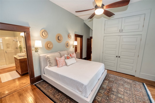 bedroom featuring light wood-type flooring, ensuite bath, a closet, baseboards, and ceiling fan