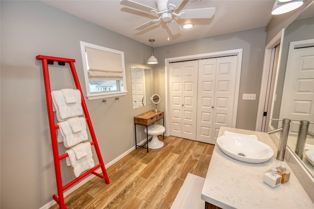 bathroom featuring vanity, wood finished floors, baseboards, a ceiling fan, and a closet