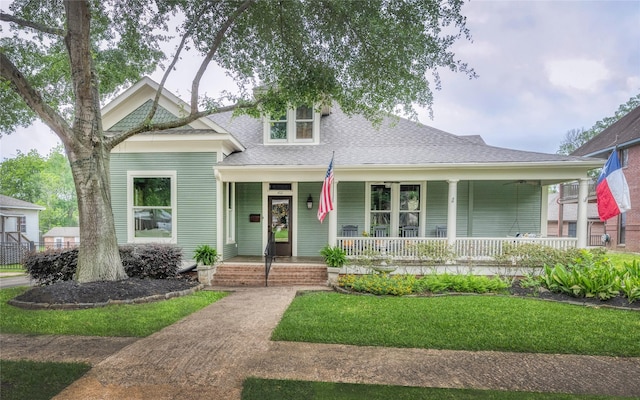 view of front of home featuring covered porch, a front lawn, and a shingled roof