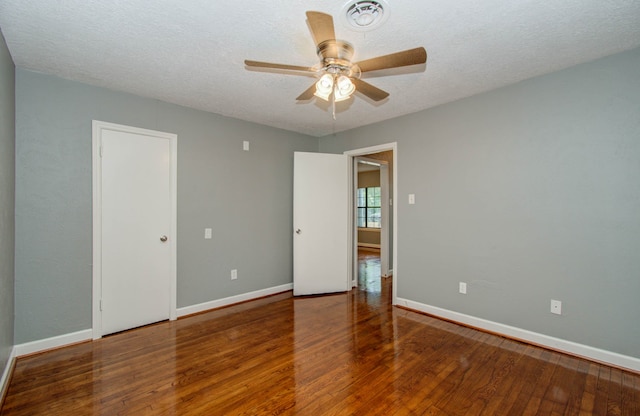 empty room featuring a textured ceiling, ceiling fan, and dark hardwood / wood-style floors