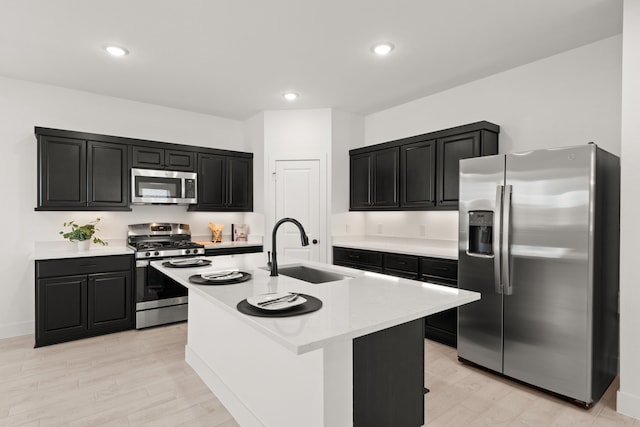 kitchen featuring appliances with stainless steel finishes, a center island with sink, light hardwood / wood-style floors, and sink