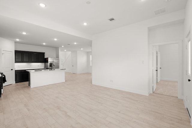 kitchen with light hardwood / wood-style flooring, an island with sink, and stainless steel refrigerator with ice dispenser