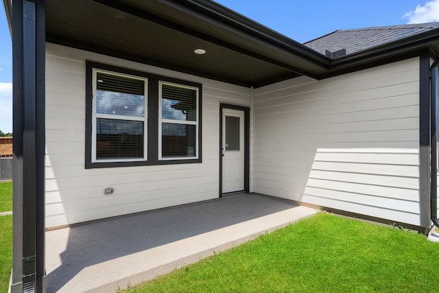 entrance to property with a lawn and a patio