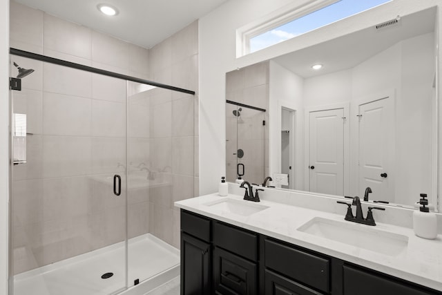 bathroom with double vanity and a shower with door