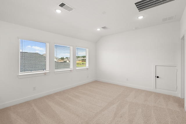 carpeted empty room with vaulted ceiling