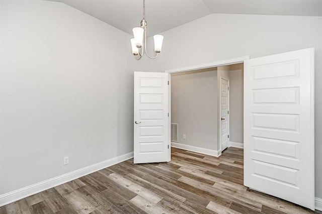 unfurnished bedroom featuring vaulted ceiling, a chandelier, and hardwood / wood-style flooring