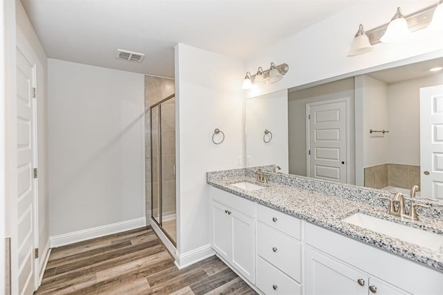 bathroom featuring dual sinks, wood-type flooring, an enclosed shower, and large vanity