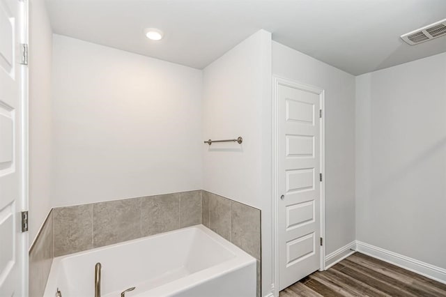 bathroom with a washtub and wood-type flooring