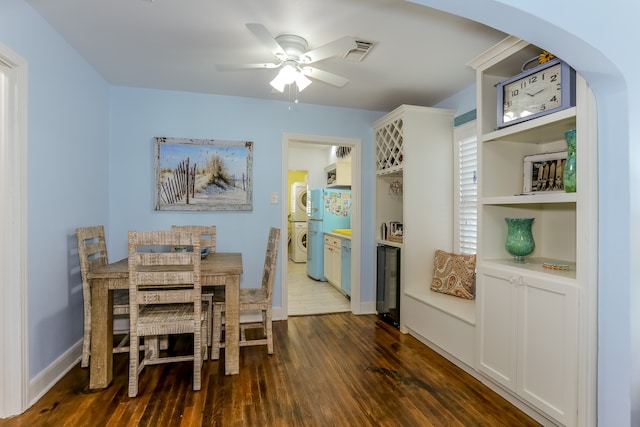 dining space with wine cooler, dark wood-type flooring, ceiling fan, and stacked washer / drying machine