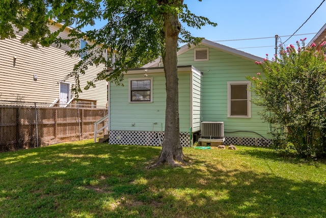 rear view of property with central AC and a lawn