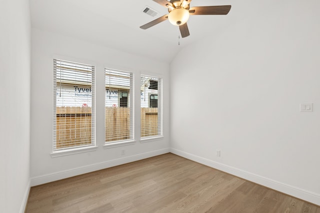 empty room with a healthy amount of sunlight, ceiling fan, light wood-type flooring, and vaulted ceiling