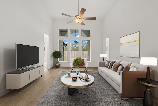 living room with ceiling fan, high vaulted ceiling, and light hardwood / wood-style flooring