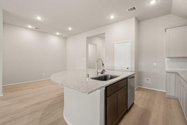 kitchen with white cabinets, light stone countertops, sink, stainless steel dishwasher, and backsplash