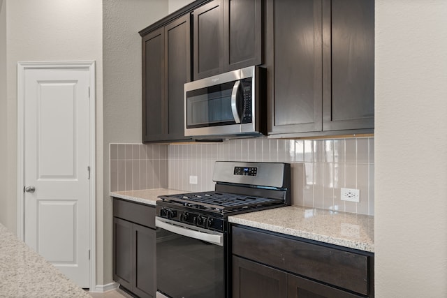 kitchen featuring light stone countertops, stainless steel appliances, dark brown cabinetry, and tasteful backsplash