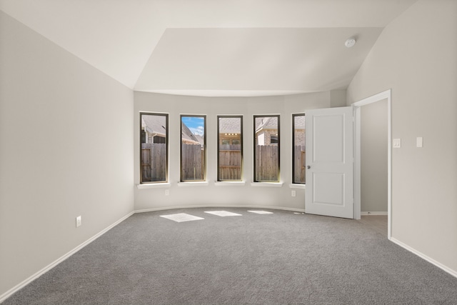 carpeted empty room with vaulted ceiling