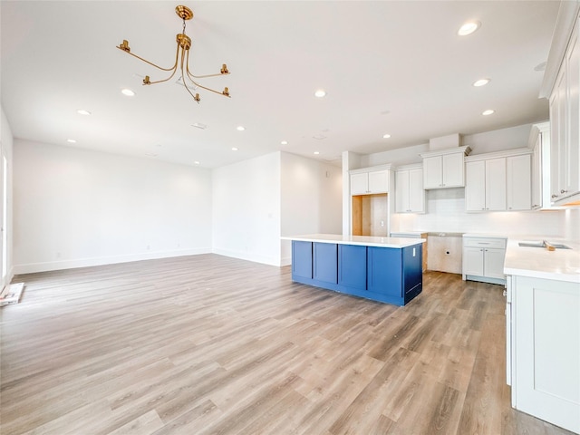 kitchen with white cabinetry, a kitchen island, light hardwood / wood-style flooring, and decorative backsplash