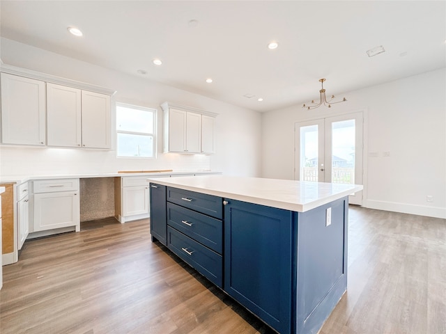 kitchen featuring white cabinetry, blue cabinets, a kitchen island, and light wood-type flooring